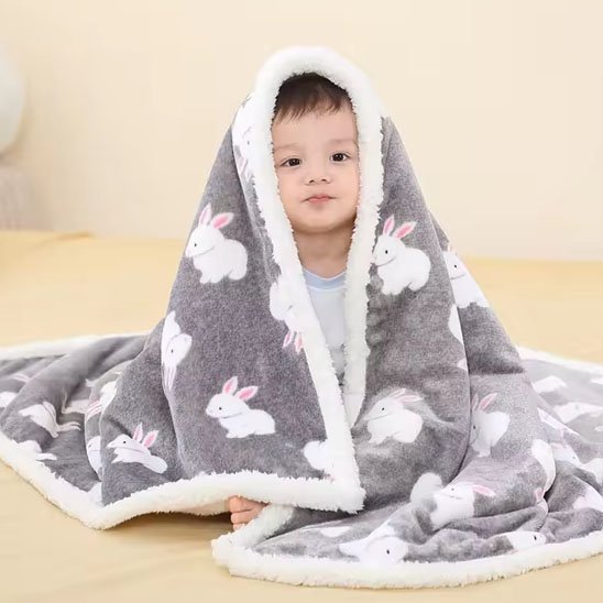 Enfant portant sur les épaules,, une couverture bébé grise avec des motifs de petits lapins blancs