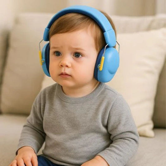 Enfant assis sur le canapé portant un casque antibruit bébé de couleur bleu