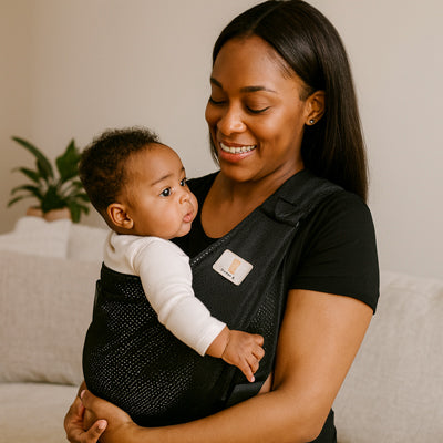 Une mère portant son bébé dans une écharpe de portage face à elle contre son torse.