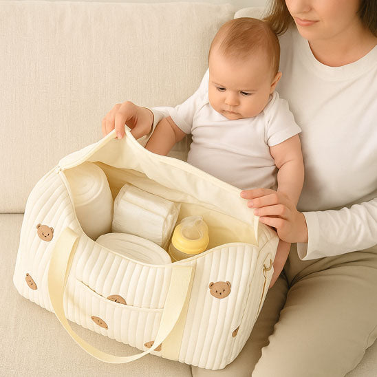 Une mère ouvrant son sac à langer beige avec son bébé sur les genoux