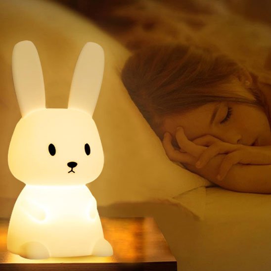 Veilleuse bébé lapin près d une petite fille endormie