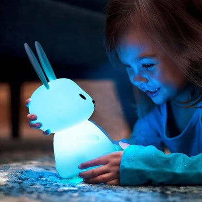 Veilleuse bébé lapin avec une lumière douce bleu entre les main d'une petite fillette