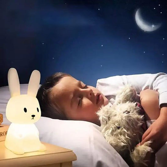 Veilleuse bébé lapin près d'un enfant endormi tenant son ours en peluche dans ses bras avec en arrière plan, un lune st des étoiles