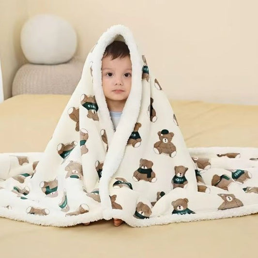 Enfant portant une couverture bébé sur les épaule beige clair avec des motifs de prtits oursons bruns
